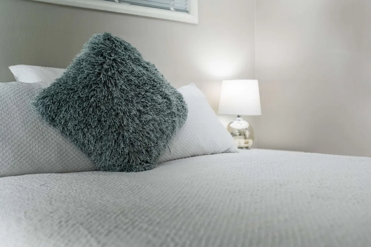 A close-up of a textured pillow and table lamp on a side table, evoking a sense of comfort and relaxation. The inviting atmosphere suggests a peaceful spot, perhaps for unwinding after a day out.