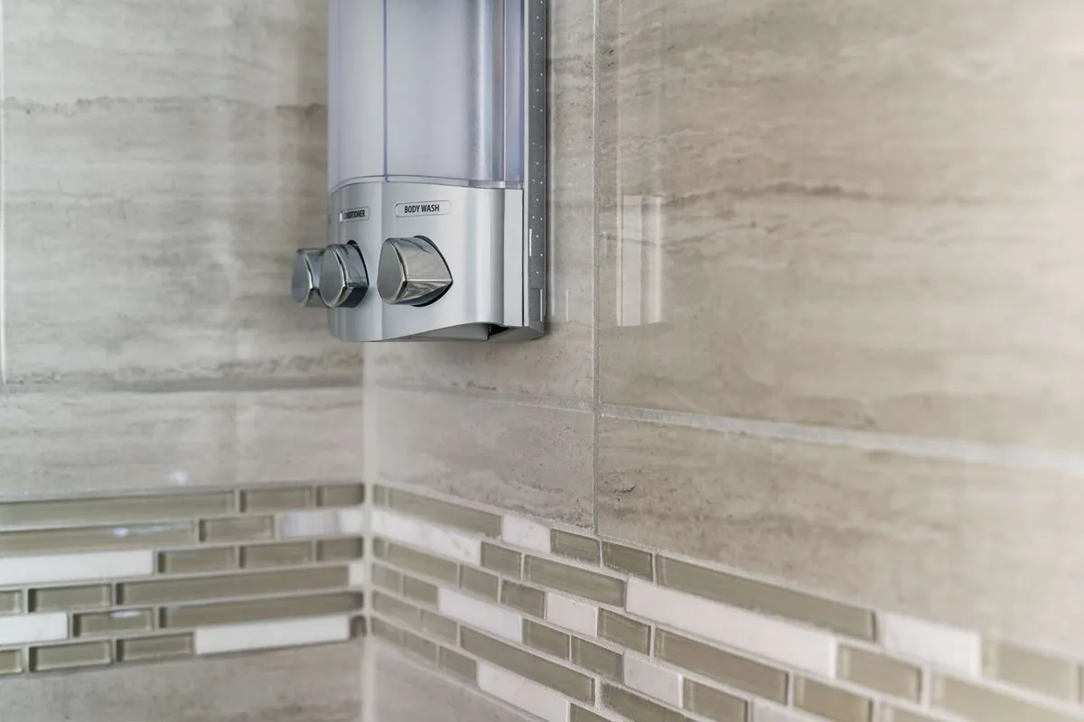 A contemporary bathroom scene with a stylish decorative tile pattern and a mounted shower dispenser. The space exudes a spa-like, rejuvenating ambiance, inviting guests to enjoy refreshing showers as part of their relaxation routine.