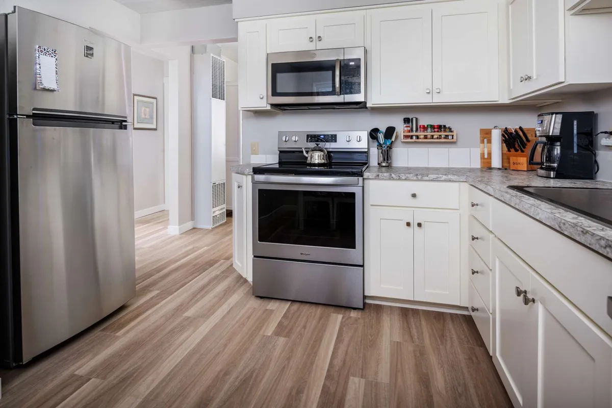 A modern kitchen with stainless steel appliances including a refrigerator, oven, and microwave, as well as a kitchen sink. The space is inviting and well-equipped for cooking or entertaining, with clean lines and a cozy atmosphere.
