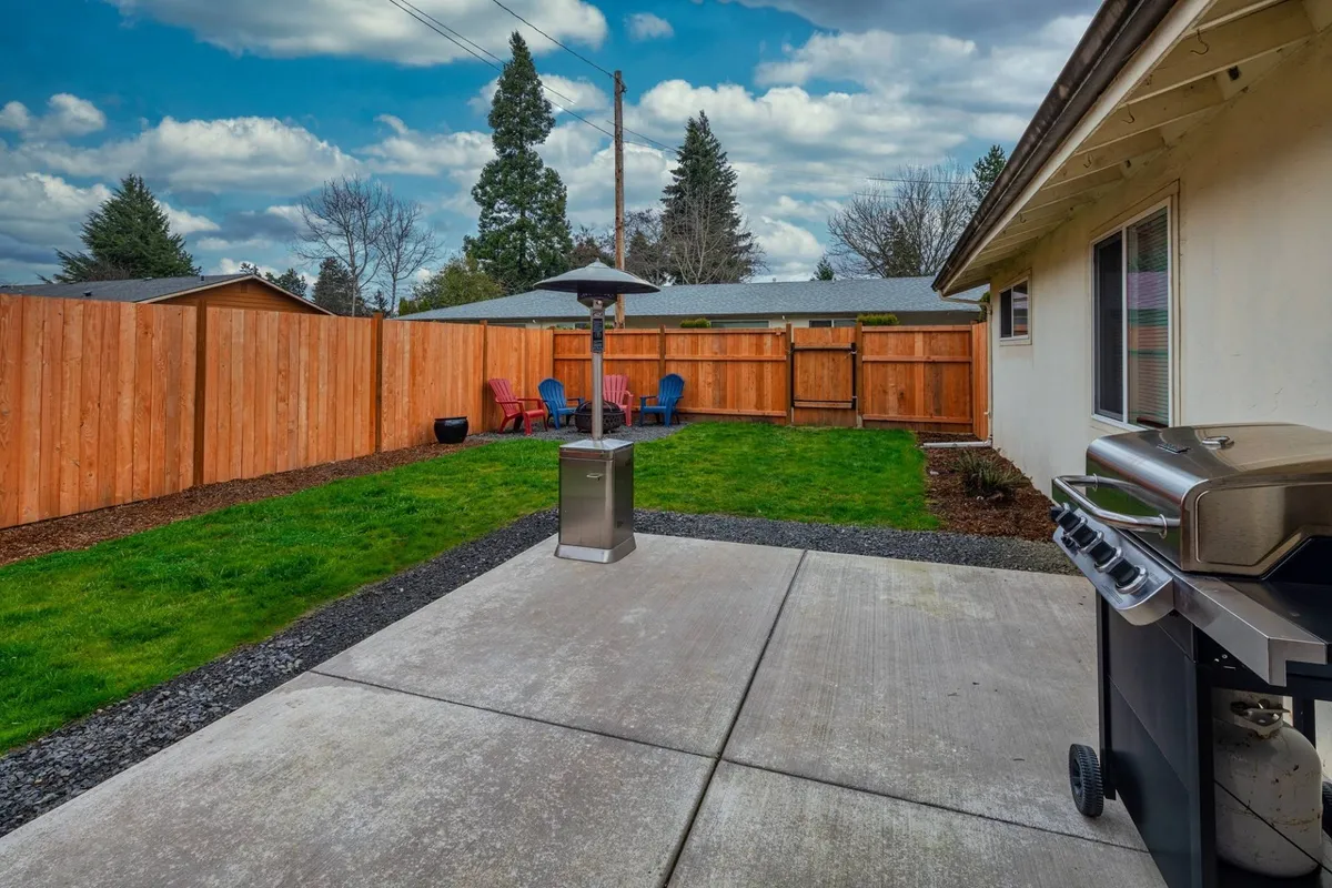 This exterior image showcases a welcoming patio area featuring a BBQ grill, outdoor heater, lawn space, and partial fencing. The area is set up for outdoor relaxation and socializing, aligning with the section's emphasis on enjoying warm Oregon evenings with a barbecue and gatherings.