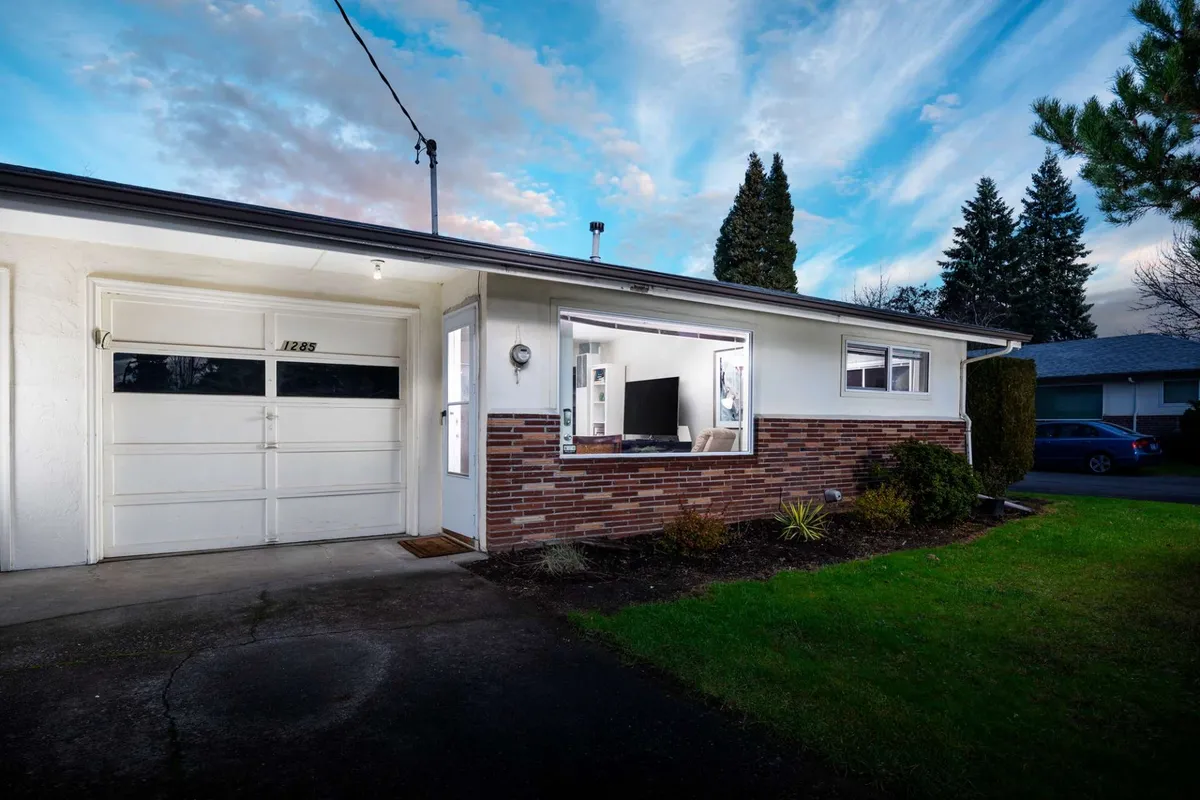 The exterior view depicts the home's landscaped front yard with a glimpse of the garage door and porch, suggesting a seamless transition from the interior to the home's welcoming outdoor spaces. The space is designed for gathering and relaxing, reflecting the home’s role as a launchpad for adventures.
